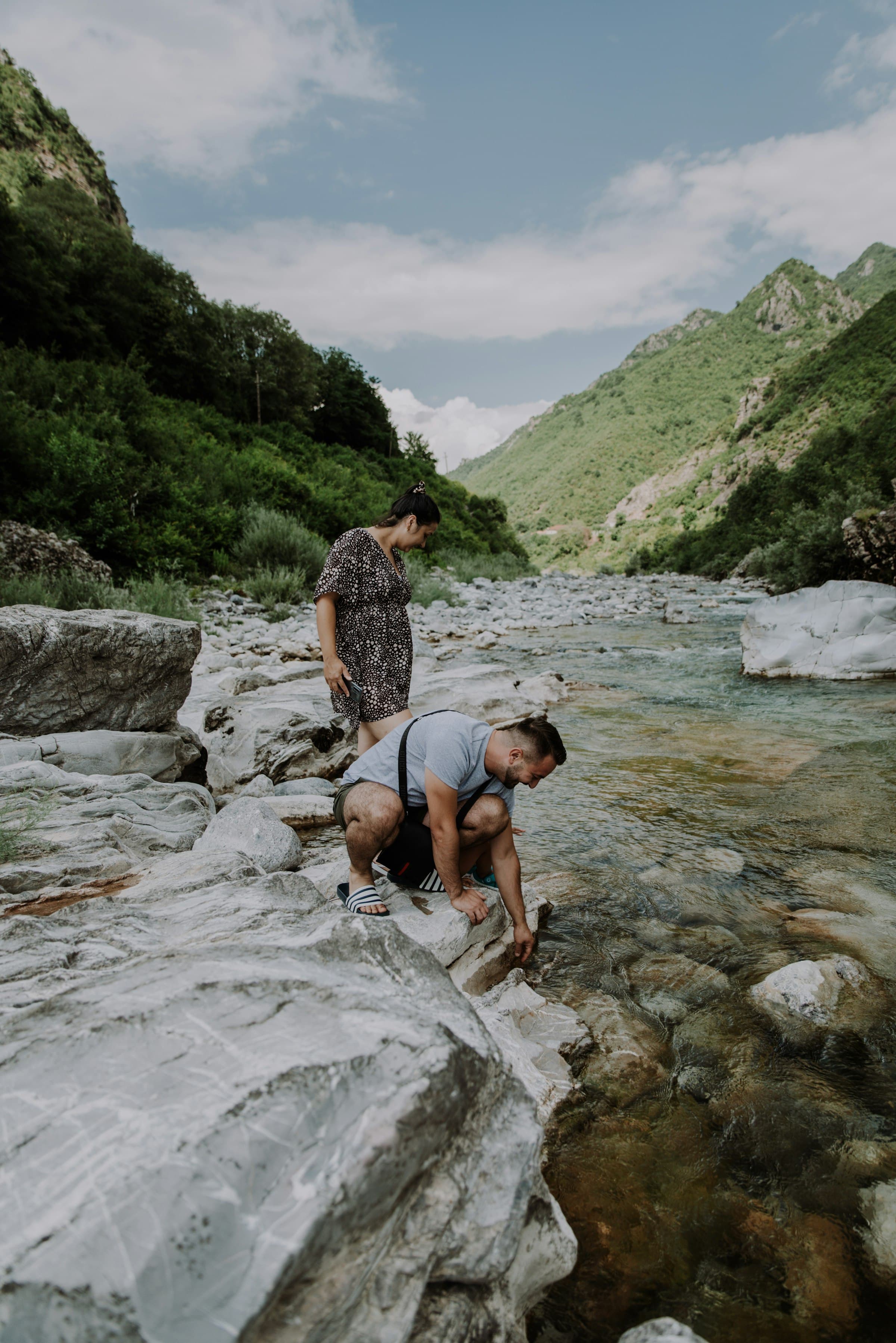 Two people beside a clear mountain river in northern Albania